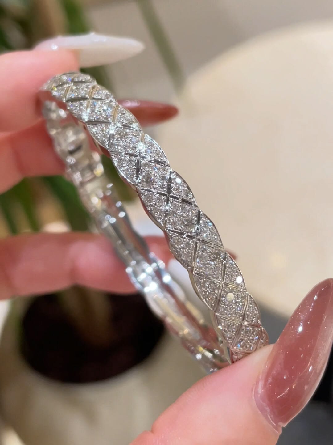 Close-up of a pavé silver bracelet held in a hand